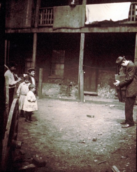 Lewis Hine taking picture near New York City tenement, 1910. 