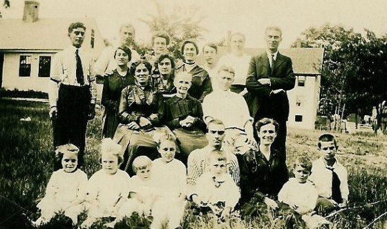 Alfred (on left, wearing tie), Eglantine (to Alfred's left, wearing dark dress), Josephine (sitting to Eglantine's left, just below her), Mamie (to Josephine's left), Agnes (standing to Mamie's left), Henry (standing on right, wearing suit), Joseph (sitting on ground behind boy), Louise (sitting to Joseph's left). Photo taken at Mill Circle, circa 1930.